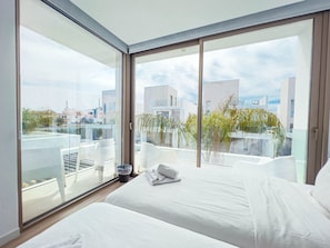 A modern hotel room with a large balcony, a bed, and a view of the cityscape. - Azure Seaview - Jade Villa (Paralimni)