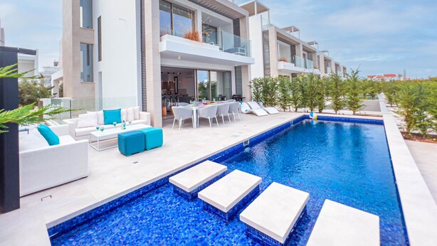 A modern hotel with a swimming pool, outdoor seating, and a covered patio area. - Azure Seaview - Jade Villa (Paralimni)