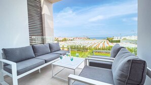 A balcony with a grey sofa and a white coffee table, overlooking a vineyard and the sea. - Azure Seaview - Jade Villa (Paralimni)