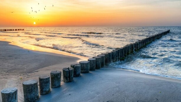 A beach with a wooden breakwater and a sunset in the background. - Island jewel in the Lindenhof with south-facing terrace (Wangerooge)