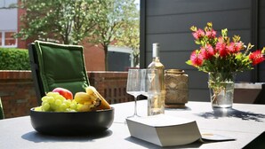 A table with a bowl of fruit, a bottle of wine, and a vase of flowers. - Island jewel in the Lindenhof with south-facing terrace (Wangerooge)