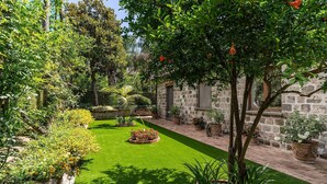 Un jardín bien cuidado con césped, plantas en macetas y un edificio de piedra.