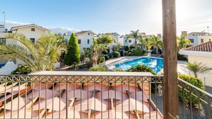 A pool area with lounge chairs, surrounded by greenery and buildings. - Villa Anna Maria (Sotira)