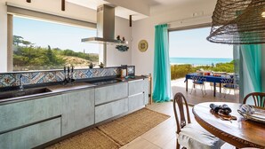 Una cucina moderna con una grande finestra che si affaccia su un panorama mozzafiato, un'area pranzo con tavolo e sedie e vista sull'oceano.