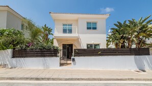 A two-story house with a balcony, a white exterior, and a small front porch. - Villa Amesta (Paralimni)