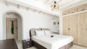 A bedroom with a bed, a nightstand, a wardrobe, and a hanging light fixture.