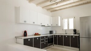 A modern kitchen with white and dark cabinets, a stainless steel refrigerator, a microwave, and a coffee maker.