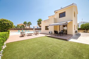 Una moderna casa a due piani con patio, posti a sedere all'aperto e piscina.