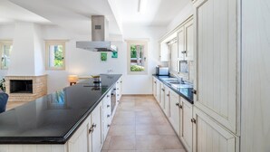 A spacious kitchen with a large island, white cabinetry, and a built-in stove. - Villa Lindo (Paralimni)