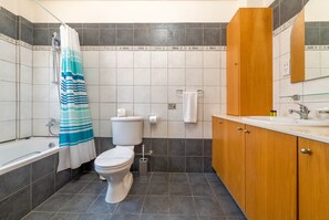 Un bagno con vasca, water e lavabo con specchio.