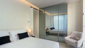 A hotel room with a large bed, a chair, a mirror, and a nightstand. - Villa Zora with pool and garden - My Rental Homes (Syracuse)