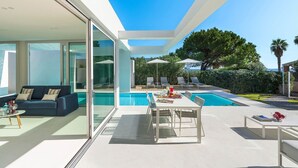 A modern outdoor living area with a pool, lounge chairs, and a dining table. - Villa Zora with pool and garden - My Rental Homes (Syracuse)