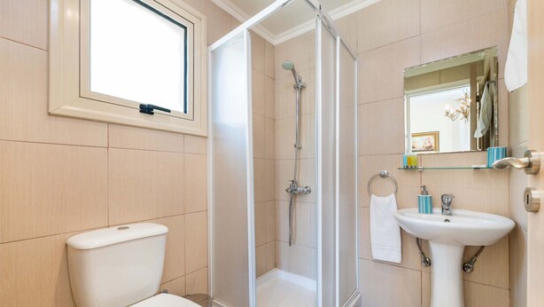 Un baño con inodoro, cabina de ducha, lavabo y espejo.
