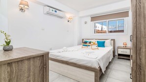 A modern hotel room with a wooden bed, bedside tables, and a window with a view. - Napa Centro Apartment (Ayia Napa)
