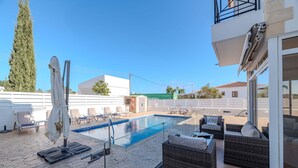 A rooftop pool area with lounge chairs, a covered umbrella, and a glass balustrade. - Nemea Serenity Blue (Ayia Napa)