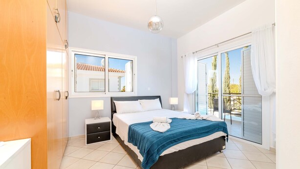 A bedroom with a bed, bedside tables, a window, and a balcony. - Nemea Serenity Blue (Ayia Napa)