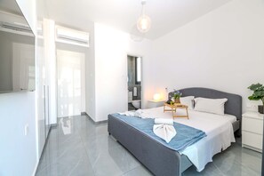 Une chambre à coucher moderne avec un lit, une table de chevet et une petite table d’appoint.