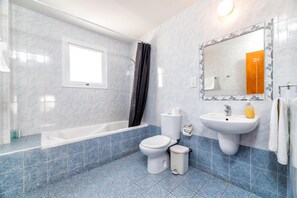Un baño con bañera, inodoro, lavabo y un espejo grande.