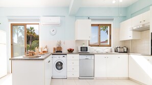 Una cocina moderna con armarios blancos, lavadora, lavavajillas y microondas.