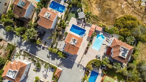 Vista aérea de una zona residencial con varias casas, cada una con piscina y tejado de baldosas.