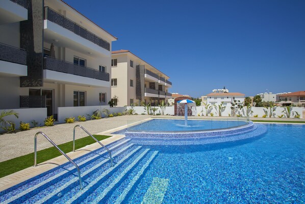 Um hotel moderno com piscina, várias varandas e um céu azul límpido.
