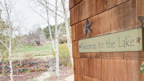 Une enseigne en bois ornée d’une étoile et portant l’inscription « Bienvenue au bord du lac », fixée à un bâtiment au style rustique.