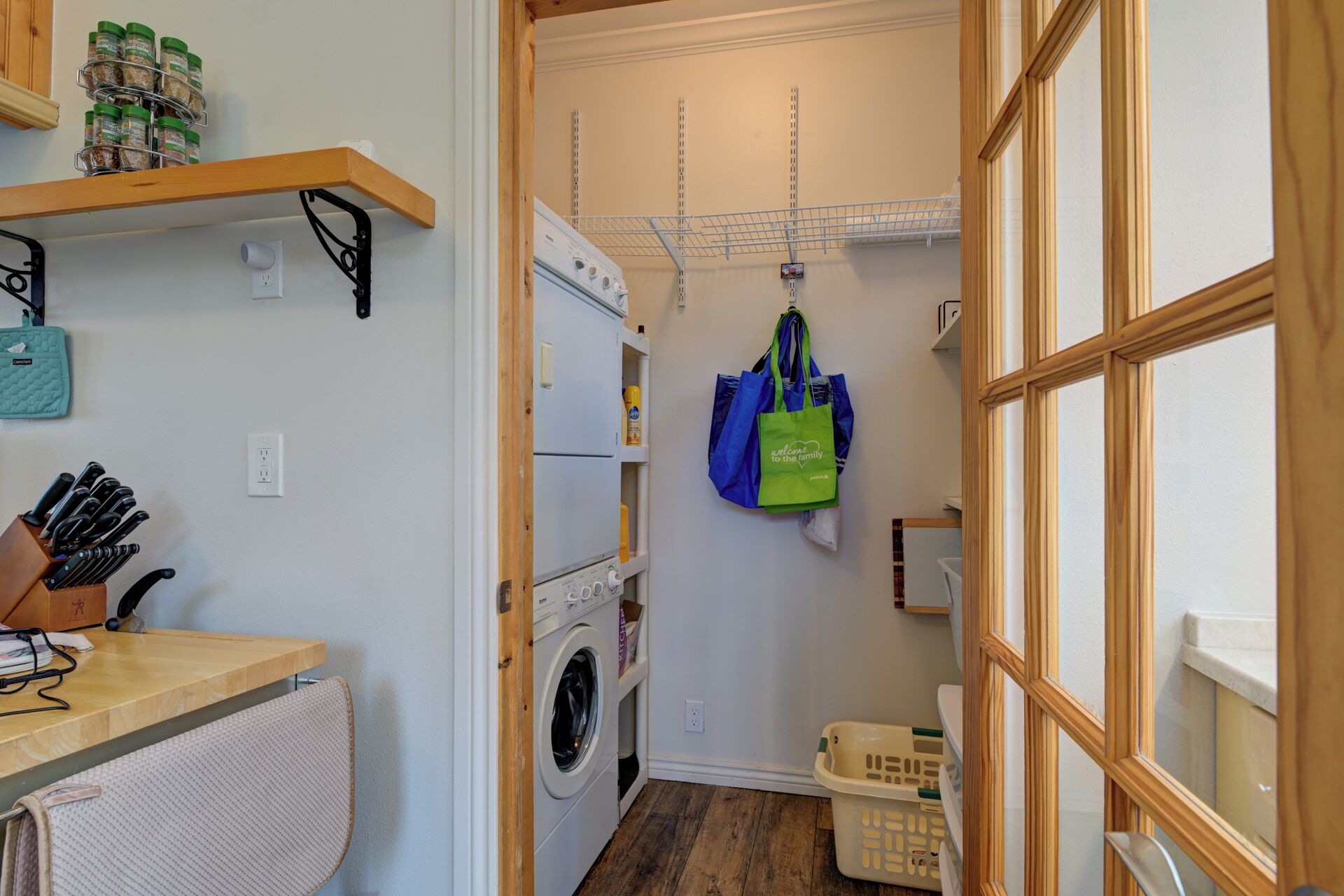 A laundry room with a washing machine, drying rack, and storage shelves.