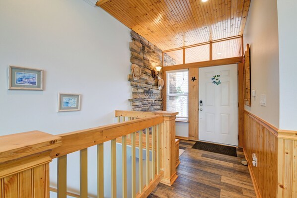 A wooden staircase leading to a room with a stone wall, a white door, and framed pictures on the wall. - Step inside our carefully crafted Oasis (Palmer Lake)