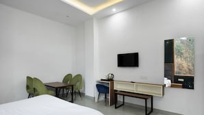 Une chambre d’hôtel comprenant un lit, un bureau avec une chaise, une télévision et un miroir.