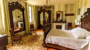 Ein Schlafzimmer mit einem großen Bett, verzierten Holzmöbeln und mehreren Spiegeln.