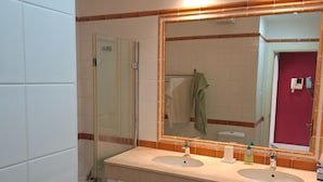 A bathroom with two sinks, a glass shower enclosure, a toilet, and a mirror with an orange frame. - Mogan Playa 19 by El Sirocco (Mogan)