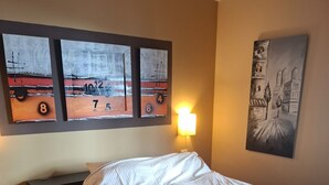 A bedroom with a bed, a nightstand, and three abstract paintings on the wall. - Mogan Playa 19 by El Sirocco (Mogan)