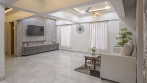 Amplia sala de estar con televisor de pantalla plana, un sofá, una mesa de centro y una planta grande.