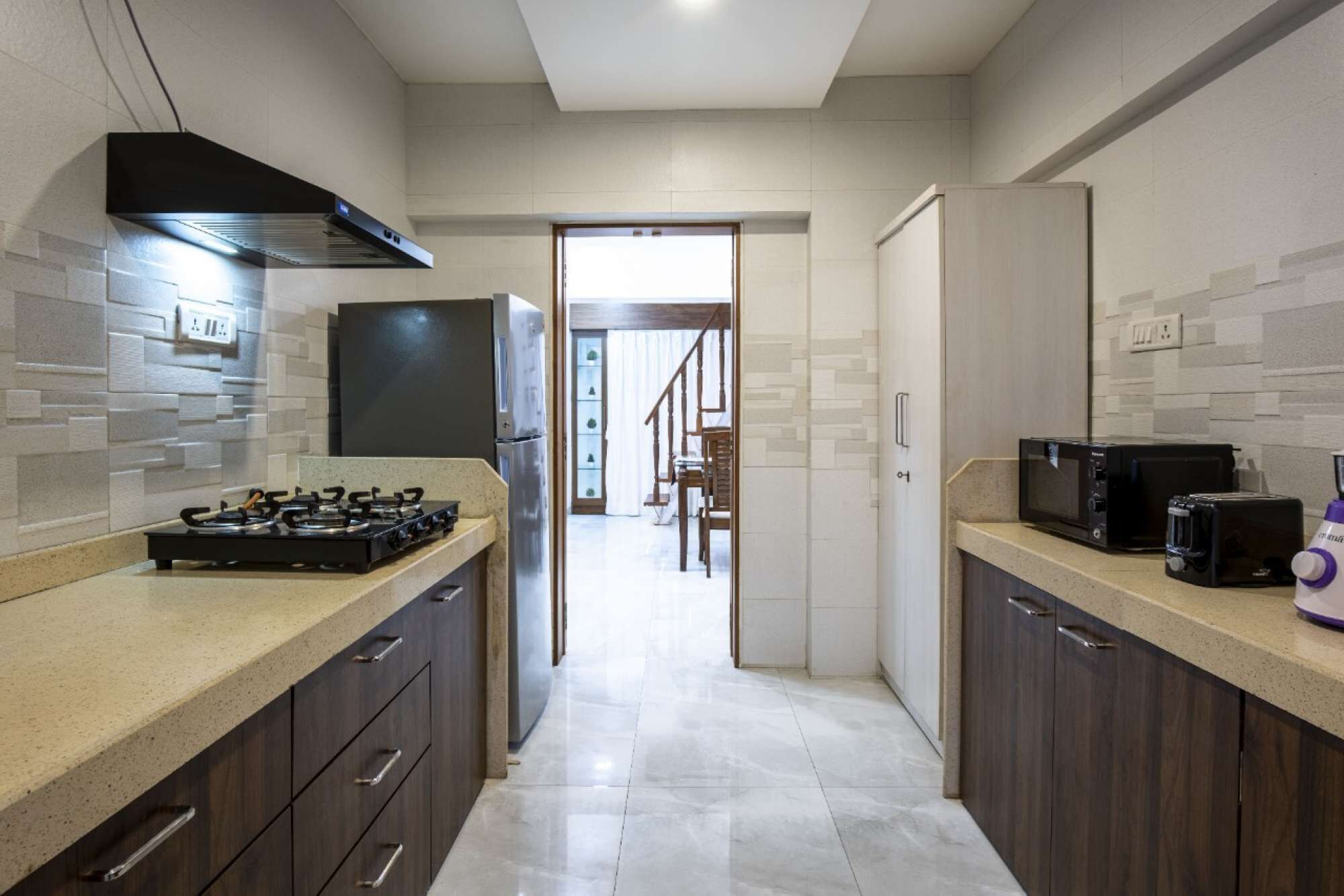 A modern kitchen with dark wooden cabinets, a gas stove, a built-in oven, a microwave, and a toaster.