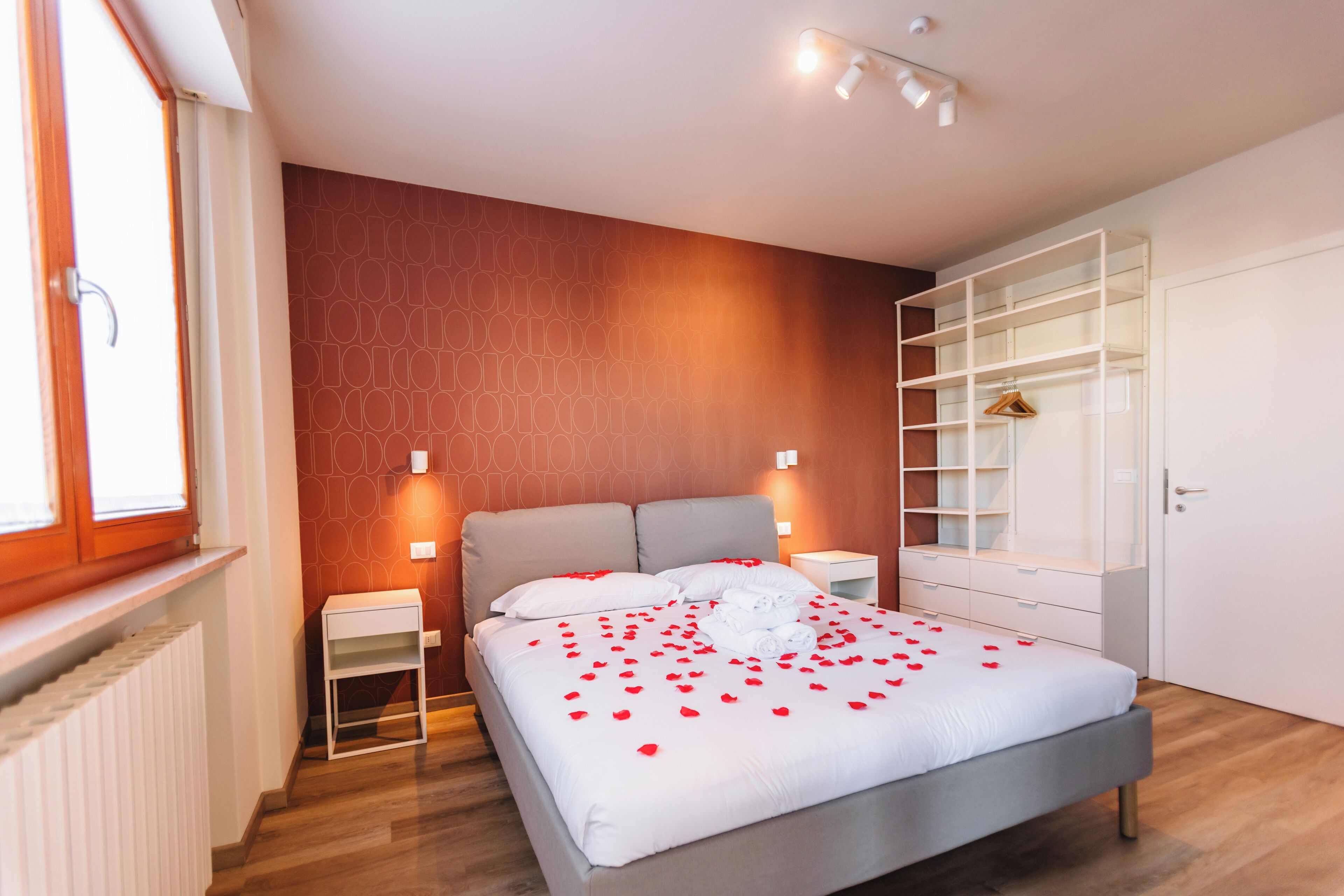 Ein modernes Schlafzimmer mit Bett, Nachttischen, einem Kleiderschrank und einem Heizkörper.