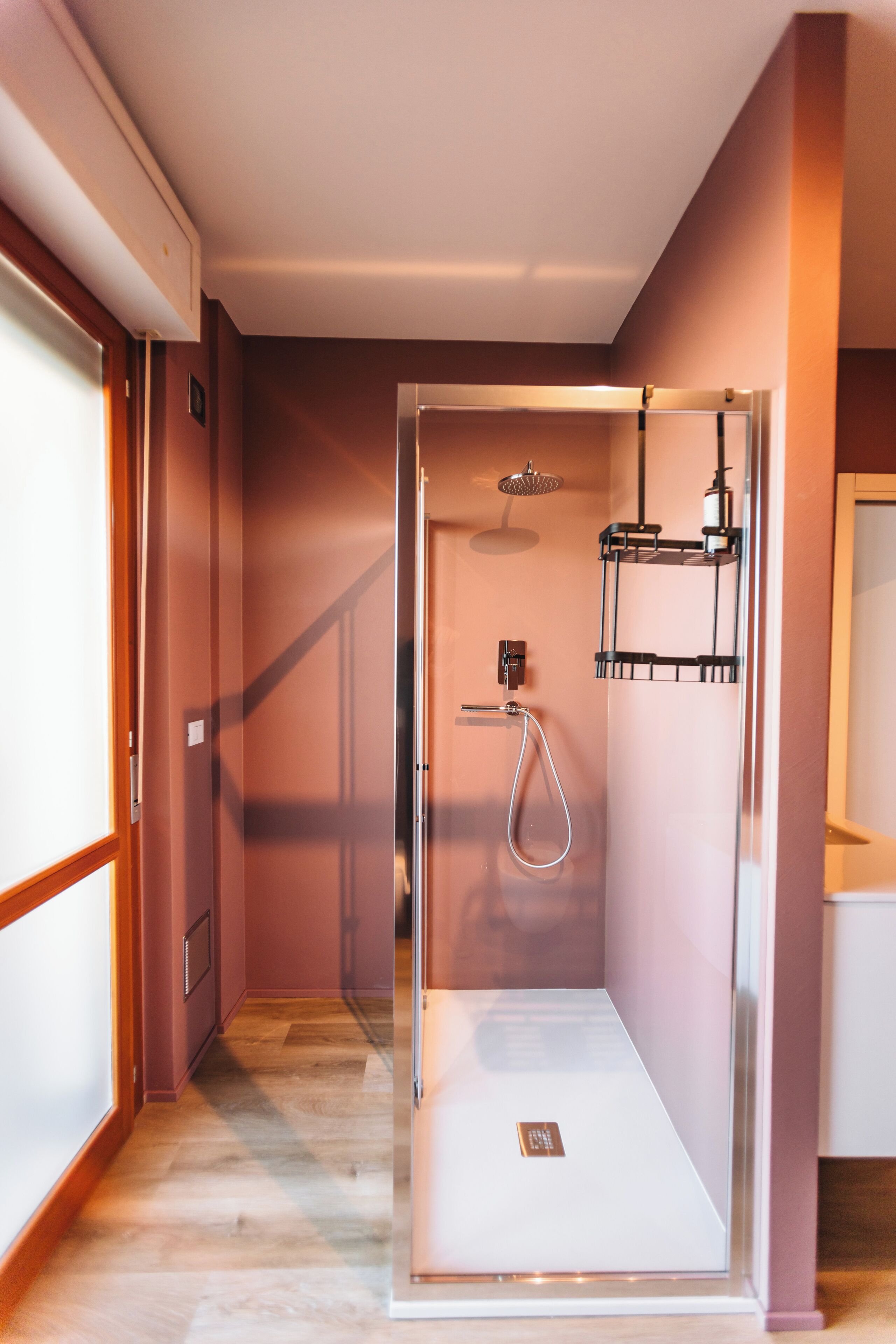 Un baño moderno con ducha envuelta en vidrio, lavamanos integrado y un perchero para toallas.