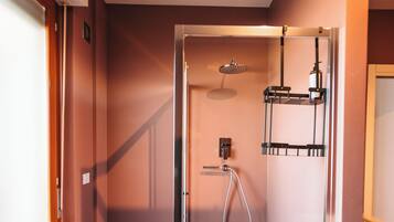 Un baño moderno con ducha envuelta en vidrio, lavamanos integrado y un perchero para toallas.