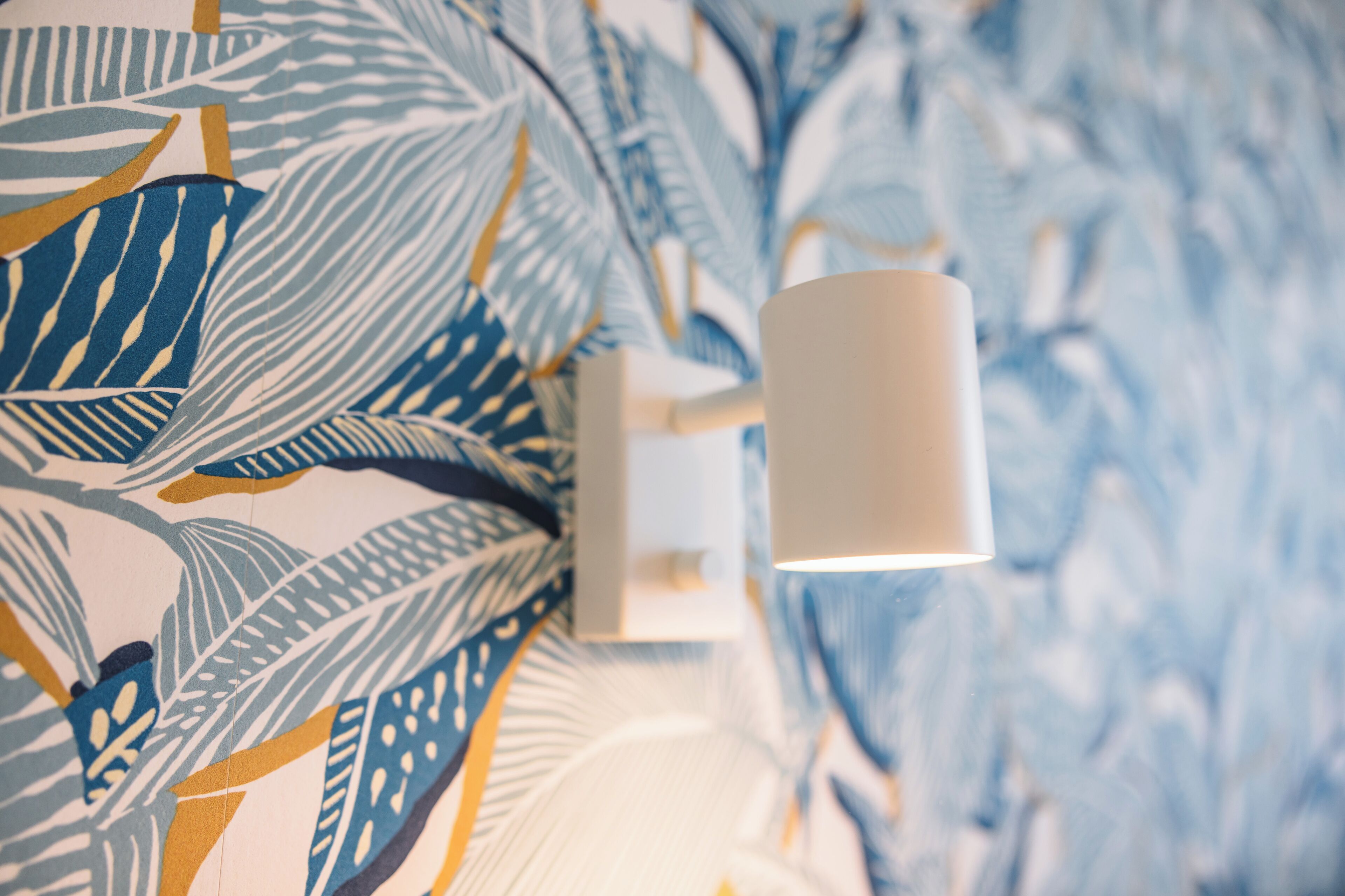 A wall with a patterned wallpaper featuring leaf designs.