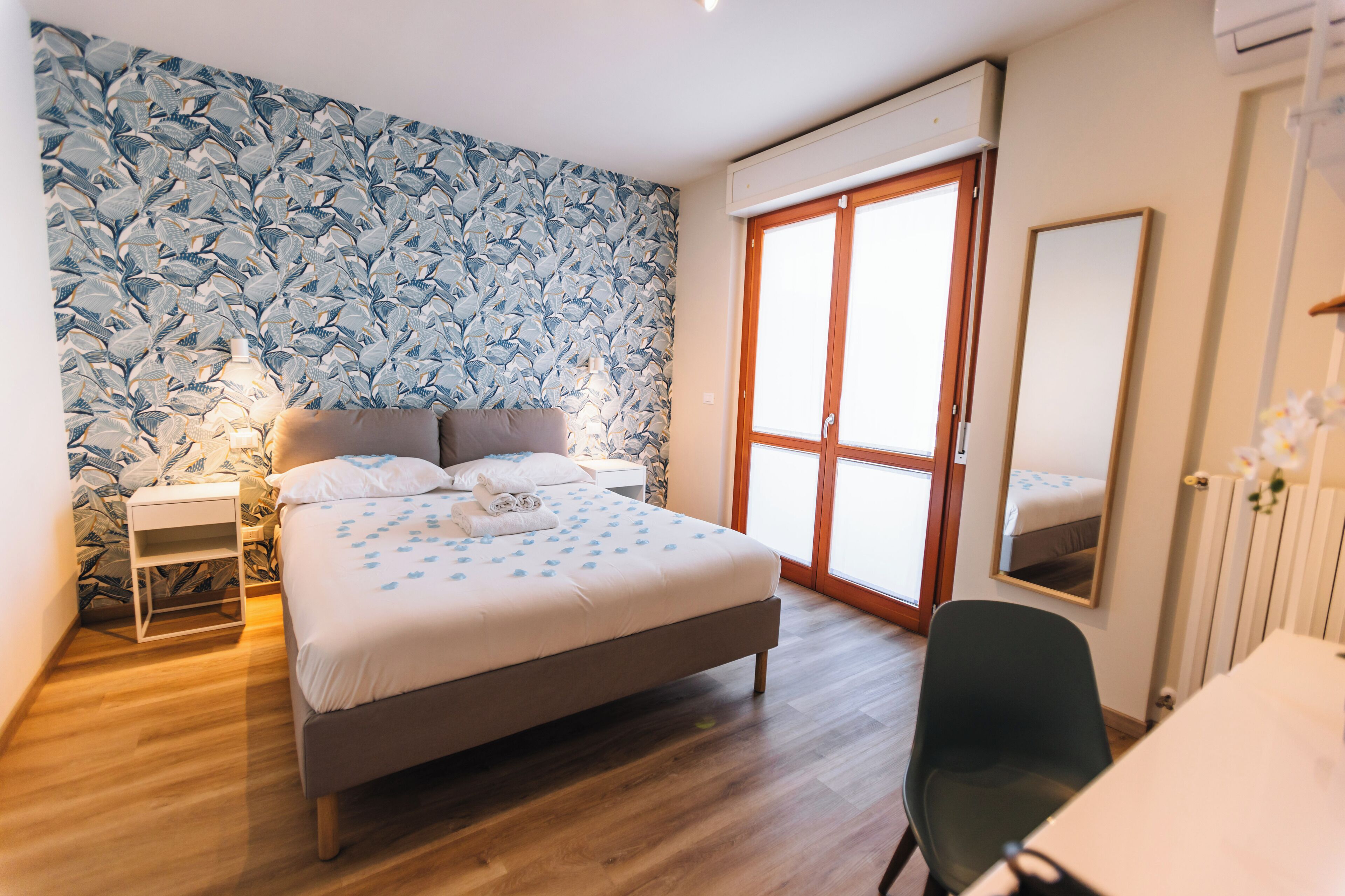 Un dormitorio con cama, mesita de noche y espejo.