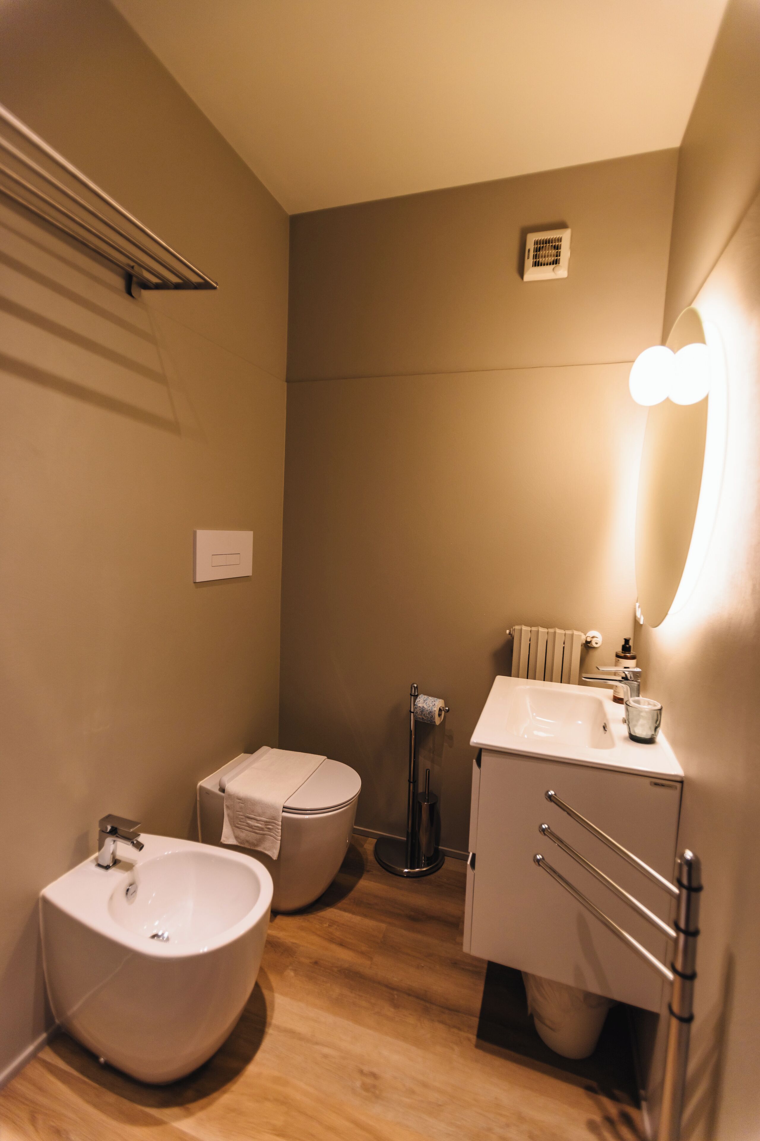 Une petite salle de bain équipée d’un bidet, de toilettes, d’un lavabo et d’un porte-serviettes.