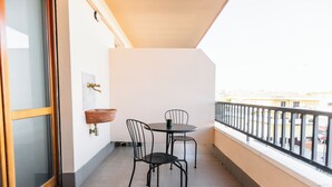 A balcony with a table and chairs, a hanging planter, and a window with a view of buildings. - La Culla dei Sogni (Pescara)