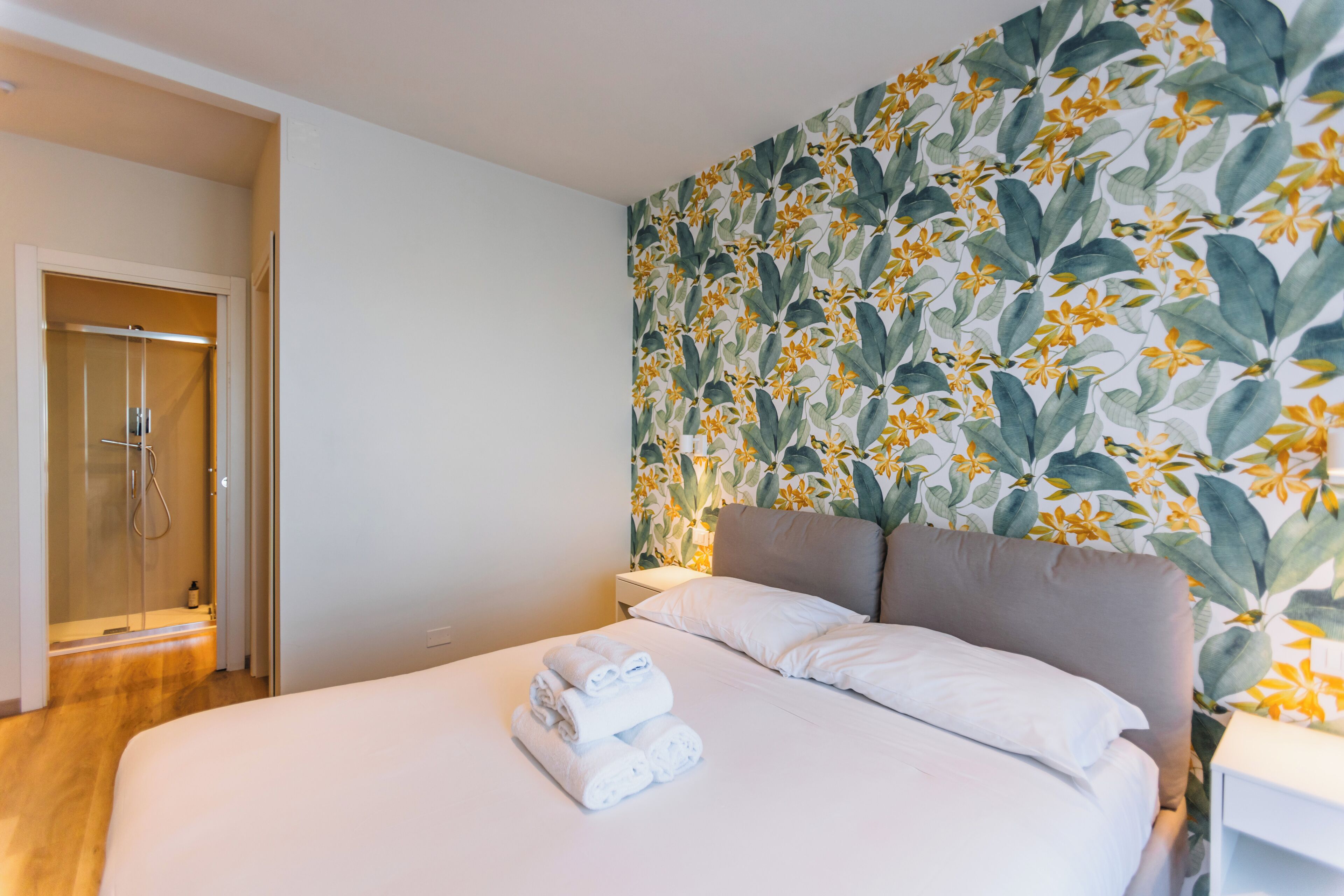 A hotel room with a bed, a shower, and a floral wallpaper.