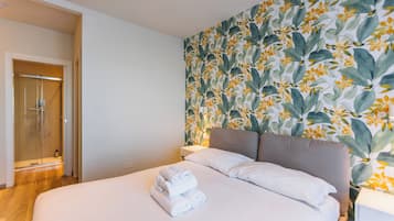 A hotel room with a bed, a shower, and a floral wallpaper.