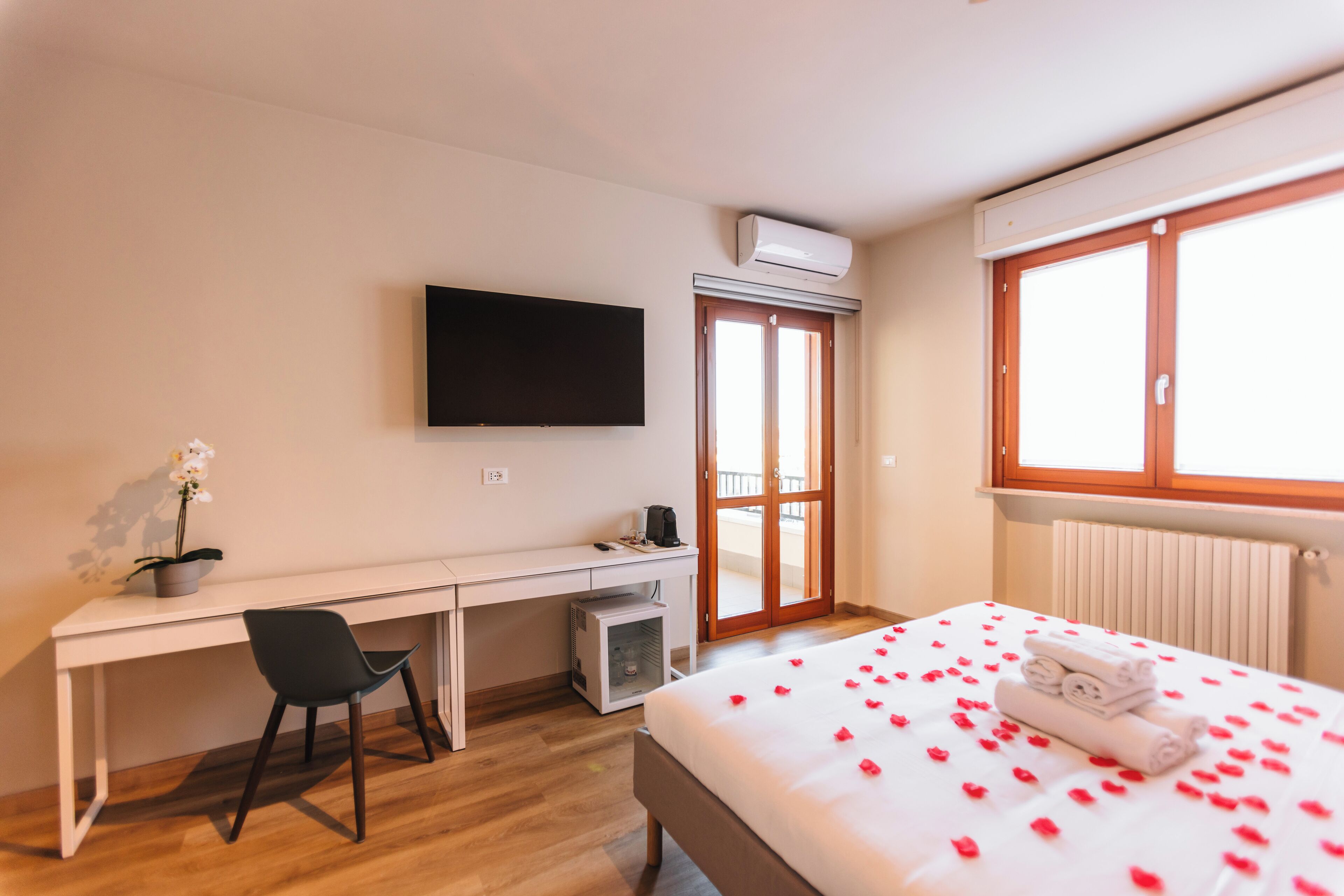 Ein Hotelzimmer mit Bett, Schreibtisch, Stuhl, Fernseher und Fenster.