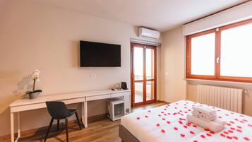 Una habitación de hotel con cama, escritorio, silla, televisor y ventana.