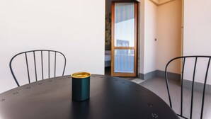 A small round table with a single teal mug, two black chairs, and a view of a balcony through a glass door. - La Culla dei Sogni (Pescara)