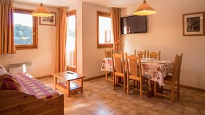 A cozy room with a bed, a small table, a dining table with chairs, a TV mounted on the wall, and a window with curtains. - Apartment for 6 in Aussois, balcony and wifi at reception (Aussois)