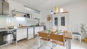 Een moderne keuken met een eethoek, roestvrijstalen apparatuur en een wit kleurenpalet.