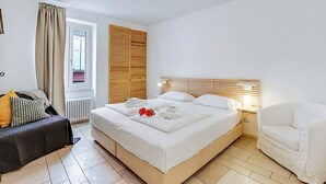 Een slaapkamer met een bed, nachtkastje, lamp en een raam met gordijnen.