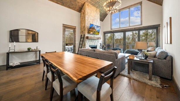 A spacious living area with a wooden dining table, grey sofas, and a fireplace. - Camp Care Free at Eagles Nest - game room, hot tub, fire pit (Banner Elk)